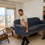 צוות מקצועי של חברת פינוי דירות מוביל ספה ורהיטים ישנים מתוך דירה באשדוד לצורך פינוי ומחזור.