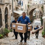 צוות פינוי דירות מקצועי מעביר ארגזים וציוד בסמטת אבן צרה ותלולה עם מדרגות בשכונת נחלאות ההיסטורית בירושלים.